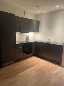 a kitchen with black cabinets and a wooden floor at Hotell Sjyen in Nesna