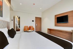 una camera con un grande letto bianco e una TV di Palette - K9 Family Restaurant a Chākan