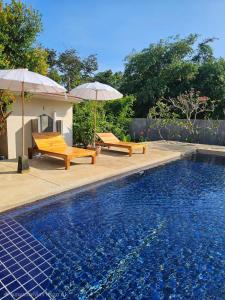 twee banken en parasols naast een zwembad bij Lanta White Rock Resort in Koh Lanta +37 foto's