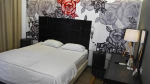1 dormitorio con 1 cama y una pared con flores en Adonis City Hotel, en Patra