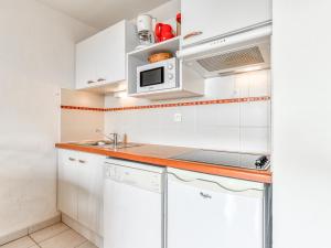 a white kitchen with a sink and a microwave at Alizea Beach A N106 2P4 in Valras-Plage