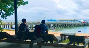 zwei Männer sitzen auf einer Bank und schauen auf den Strand in der Unterkunft Chomjan Hostel in Ko Phayam + 50 Fotos