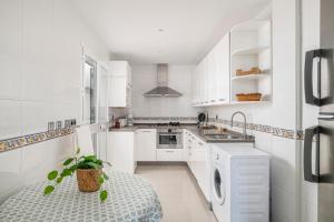 a kitchen with white cabinets and a table with a plant at Rincón del Sur in Vejer de la Frontera +20 photos