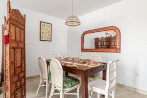 a dining room table with white chairs and a mirror at Rincón del Sur in Vejer de la Frontera