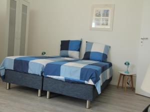 un letto con lenzuola bianche e blu in una stanza di Stunning apartment in Schoorl, North Hollandâ you can bike to the beach a Schoorl