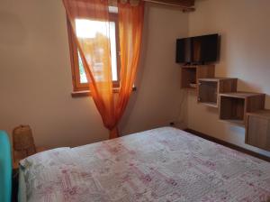 una camera da letto con un letto, una finestra e una televisione di Grazioso appartamento con giardino e posto auto a Belluno