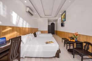 a bedroom with a bed and a desk with a laptop at Sala Hoi An Hotel in Hoi An