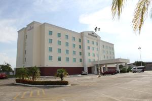 un grand bâtiment blanc avec des palmiers dans un parking dans l'établissement Rio Vista Inn Business High Class Hotel Poza Rica, à Poza Rica de Hidalgo