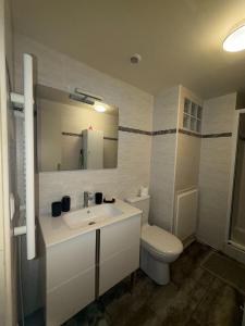 een badkamer met een wastafel, een toilet en een spiegel bij Studio cosy et calme à Garches in Garches