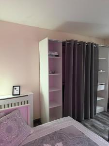 een slaapkamer met een bed en een kast met gordijnen bij Studio cosy et calme à Garches in Garches