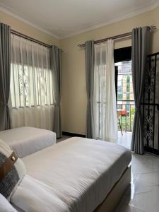 a bedroom with two beds and a window with curtains at Sunset Statehouse View Residence A in Entebbe