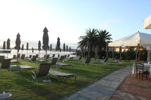 ポルト・サン・パーオロにあるIHR Hotel San Paoloの芝生の椅子・テーブル・傘
