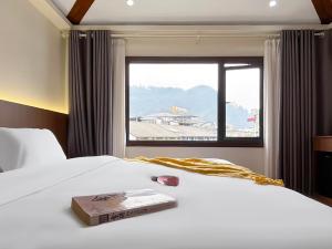 a book on a bed in a room with a window at Yijingju Humanistic Inn in Zhangjiajie