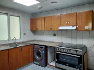 a kitchen with a stove and a washer and dryer at Orient Tower in Ajman 