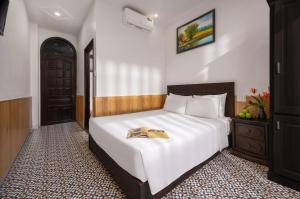 a bedroom with a bed with a book on it at Sala Hoi An Hotel in Hoi An
