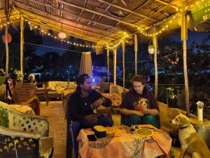 a group of three people sitting at a table with a dog at JeeHaa Homestay in Alleppey