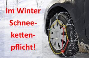 Ein Reifen, der im Schnee an ein Auto gekettet ist. in der Unterkunft Gasthof Maria Kirchental in Sankt Martin bei Lofer