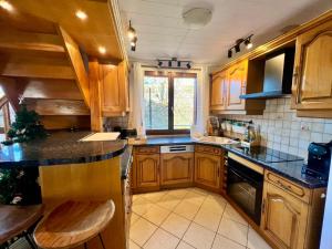 a kitchen with wooden cabinets and a black counter top at Le Chalet des 4 Chouettes in Gérardmer