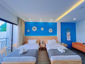two beds in a room with a blue wall at Holabay Resort in Panglao Island