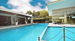 ein großer blauer Swimmingpool neben einem Haus in der Unterkunft Avenue Suites in Bacolod City