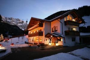 a large building with lights on in the snow at Garni la Bercia in Selva di Val Gardena