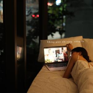 a woman laying in bed using a laptop computer at Mira Grand Hotel Quy Nhơn in Quy Nhon +31 photos