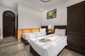 a hotel room with two beds and a door at Sala Hoi An Hotel in Hoi An