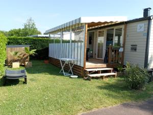 a tiny house in the yard with a porch at mobil-home 468 in Saint-Georges-dʼOléron
