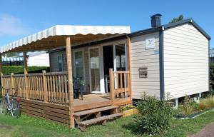 a tiny house with a porch and a deck at mobil-home 468 in Saint-Georges-dʼOléron