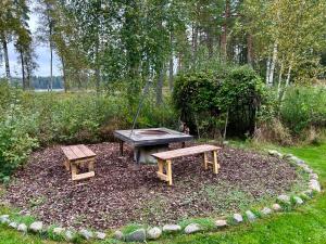 een picknicktafel en twee banken in de tuin bij Modern Peninsula Cabin With Panoramic View in Piggaboda