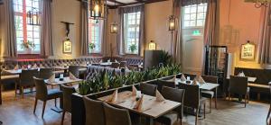 a restaurant with tables and chairs in a room with windows at Kloster Langwaden in Grevenbroich