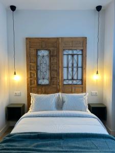 a bedroom with a large bed with two windows at La Baltasara Apartments in Valladolid