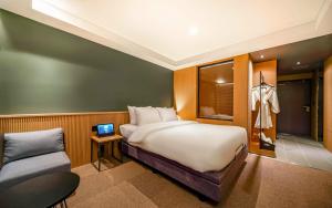 een slaapkamer met een groot wit bed en een stoel bij Haeundae The Van Hotel in Busan