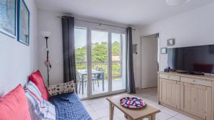 a living room with a couch and a tv and a balcony at Allee des Dunes E N57 3P6 in Ondres