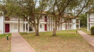 a building with trees and a sidewalk in front at Allee des Dunes E N57 3P6 in Ondres