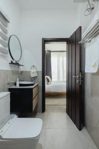 ein Badezimmer mit Toilette, Waschbecken und Spiegel in der Unterkunft The Avery at Lapwing Place in Accra + 193 Fotos