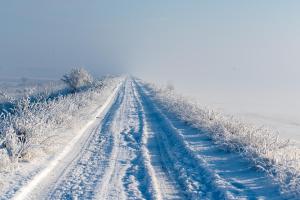a snow covered road in the middle of a field at Curte la Munte - charming village house in Sebeşu de Sus