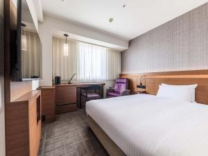 a hotel room with a bed and a desk at Nishitetsu Hotel Croom Hakata in Fukuoka