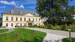 een groot wit huis met een tuin ervoor bij Zámeček Petrovice in Petrovice u Karviné