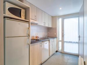 a kitchen with white cabinets and a white refrigerator at Sud Ocean J N74 2P4 in Guidel