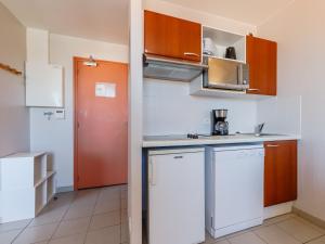 a small kitchen with white appliances and a red door at L Ocean N40 2P5 in La Tranche-sur-Mer +10 photos