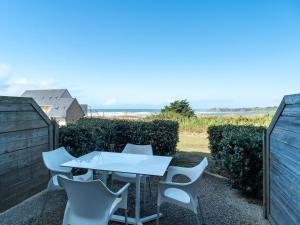 a table and chairs on a patio with the ocean in the background at Sud Ocean M N105 2P5 in Guidel