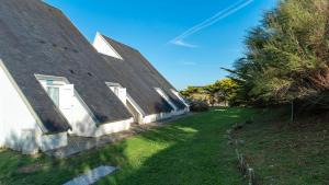 a house with a black roof and a green yard at Sud Ocean L N94 2P4 in Guidel