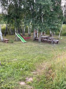 a park with a hammock and picnic tables and trees at namelis tyloje in Šarkiškės