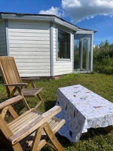 a picnic table and a chair next to a cabin at namelis tyloje in Šarkiškės