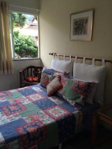 a bedroom with a quilt on a bed with a window at Pousada HospedaBia in Teresópolis