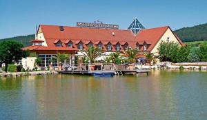 a large building with a dock on a body of water at Fichtelgebirgshof in Himmelkron