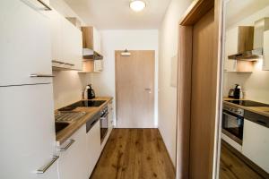 eine Küche mit weißen Schränken und Holzböden in der Unterkunft Oscar & Sons Apartments in Piesendorf