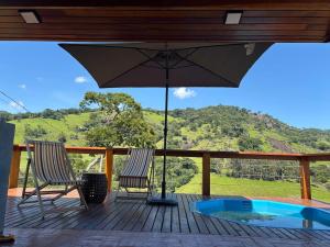 a deck with two chairs and an umbrella at Aura dos Ipês in Paraisópolis