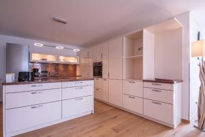 a kitchen with white cabinets and a hardwood floor at Traumwohnung in Norderney